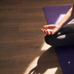 woman's hand and leg folded on yoga mat
